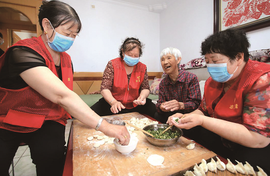 北京市延庆区八达岭镇岔道村志愿服务队队员们和77岁的服务对象孙秀兰一起包饺子。